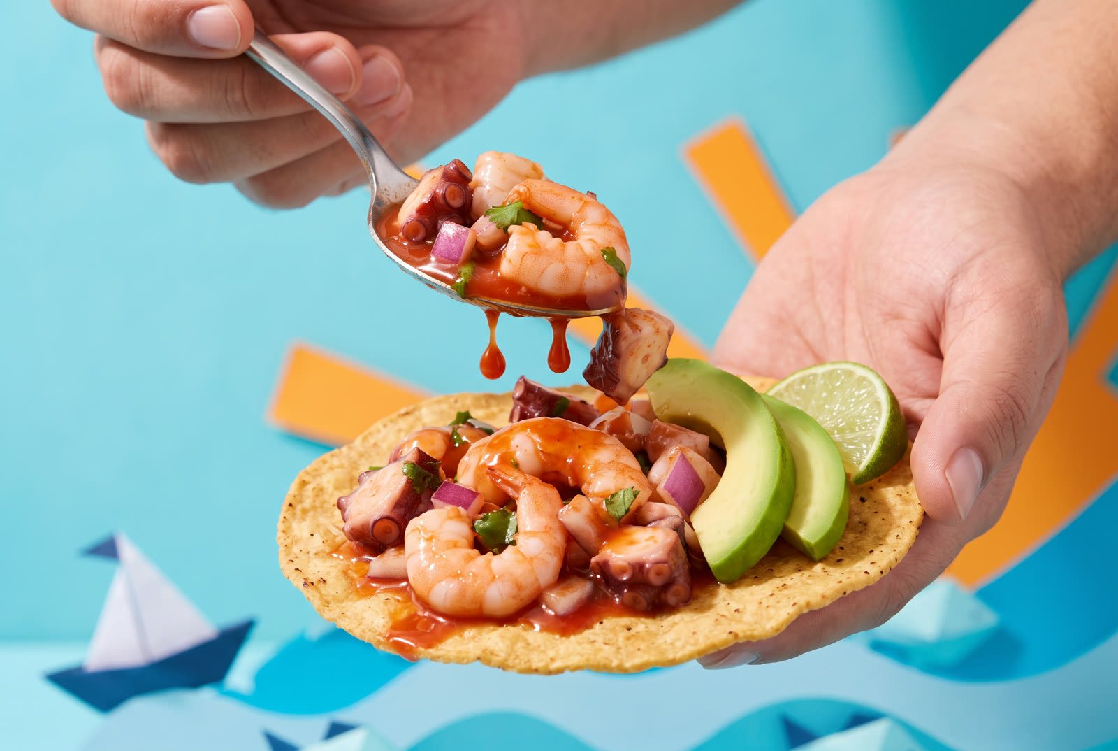 Manos armando una tostada de mariscos